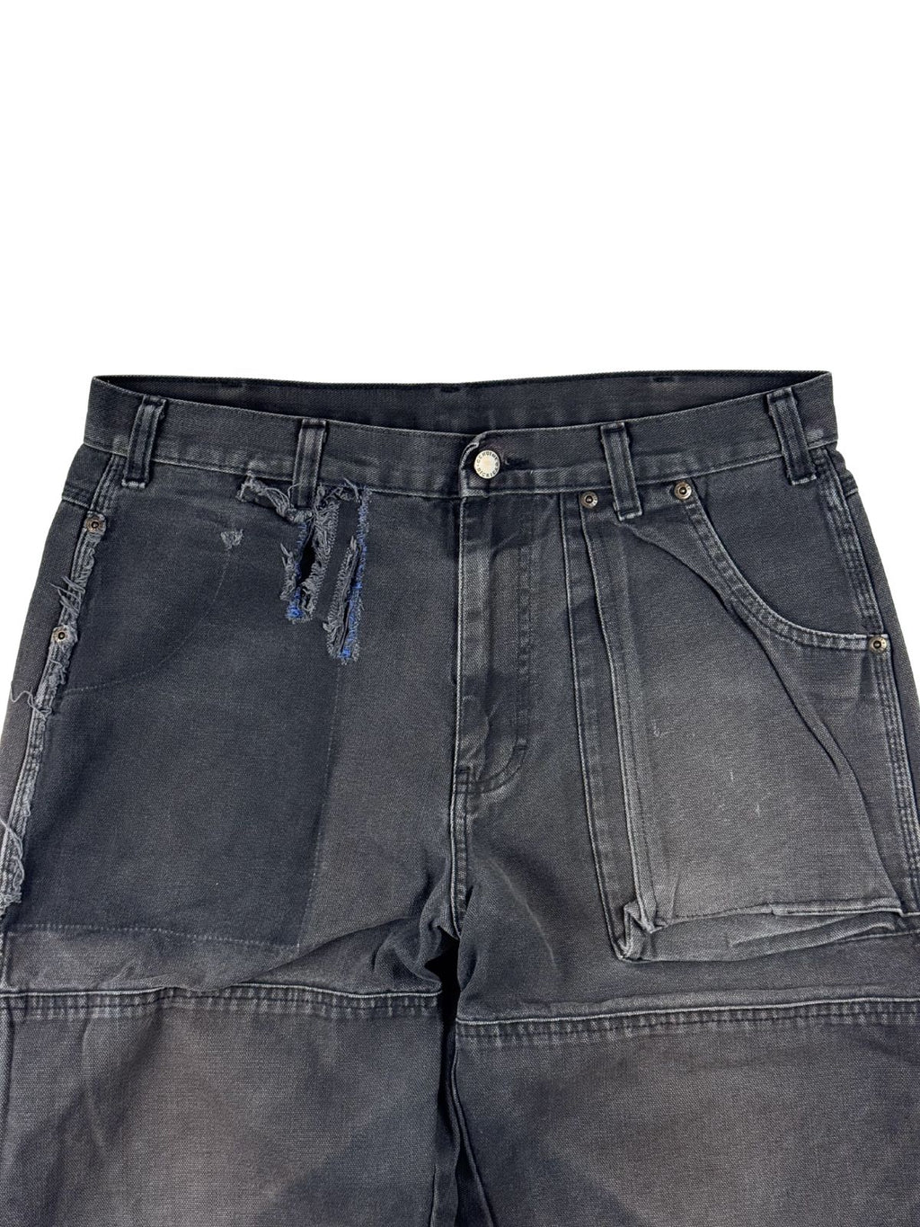 Detailaufnahme des vorderen Bunds der Dickies Hose mit einem markanten, vertikalen Riss auf der rechten Seite und einem interessanten „Ghost Pocket“-Effekt (Abdruck einer ehemals aufgesetzten Tasche) auf der rechten Seite.