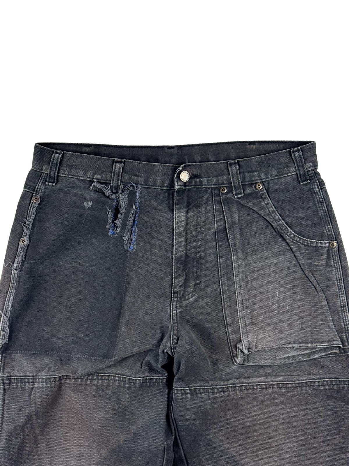 Detailaufnahme des vorderen Bunds der Dickies Hose mit einem markanten, vertikalen Riss auf der rechten Seite und einem interessanten „Ghost Pocket“-Effekt (Abdruck einer ehemals aufgesetzten Tasche) auf der rechten Seite.