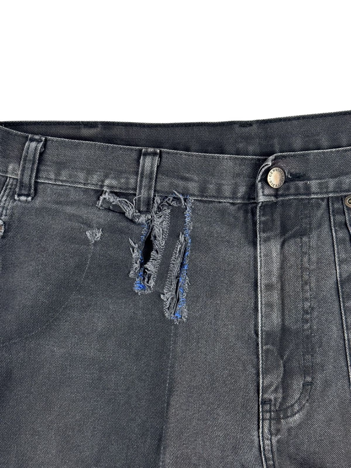 Makroaufnahme des großen, thrashed Stoffrisses unterhalb der Gürtelschlaufe, der den rauen Distressed-Charakter der Skate-Hose betont.