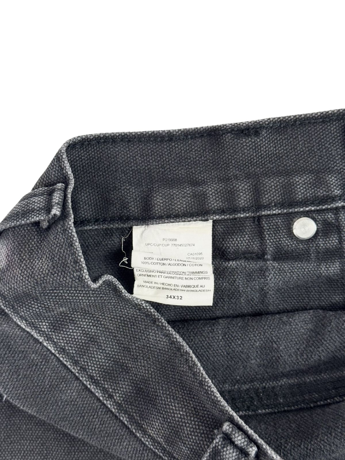 Detailansicht des inneren weißen Stoffetiketts (Care & Size Tag) am Hosenbund mit der Größenangabe „34x32“, dem Materialhinweis „100% COTTON“ und dem Herkunftsland Bangladesh.