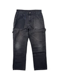 Vintage Dickies Double Knee Carpenter Hose in der kompletten Frontansicht. Ausgewaschene, anthrazit-schwarze Workwear-Hose im Thrashed-Look mit ausgeprägtem Kniefading, einem großen Stoffriss rechts und markantem Ghost-Pocket-Effekt rechts.
