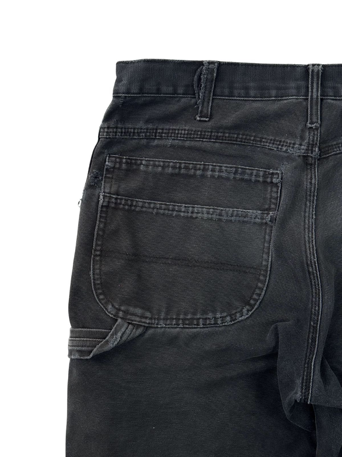 Detail der linken Gesäßtasche einer Vintage Dickies Workwear Hose mit doppelter Naht und authentisch verwaschenem schwarzen Canvas-Stoff.