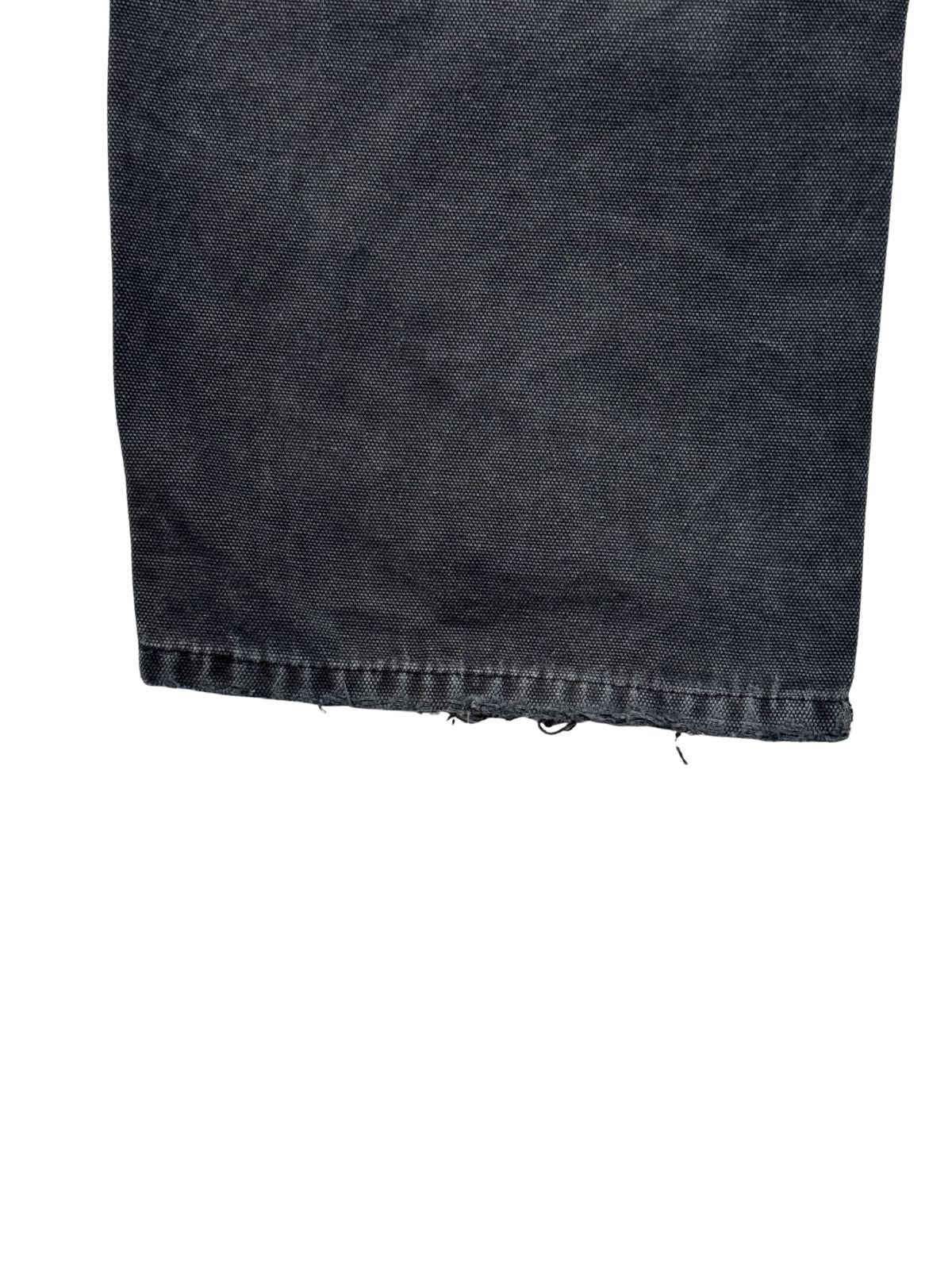 Detailansicht der abgenutzten Saumkante am linken Bein einer verwaschenen schwarzen Dickies Double Knee aus strapazierfähigem Baumwoll-Canvas.