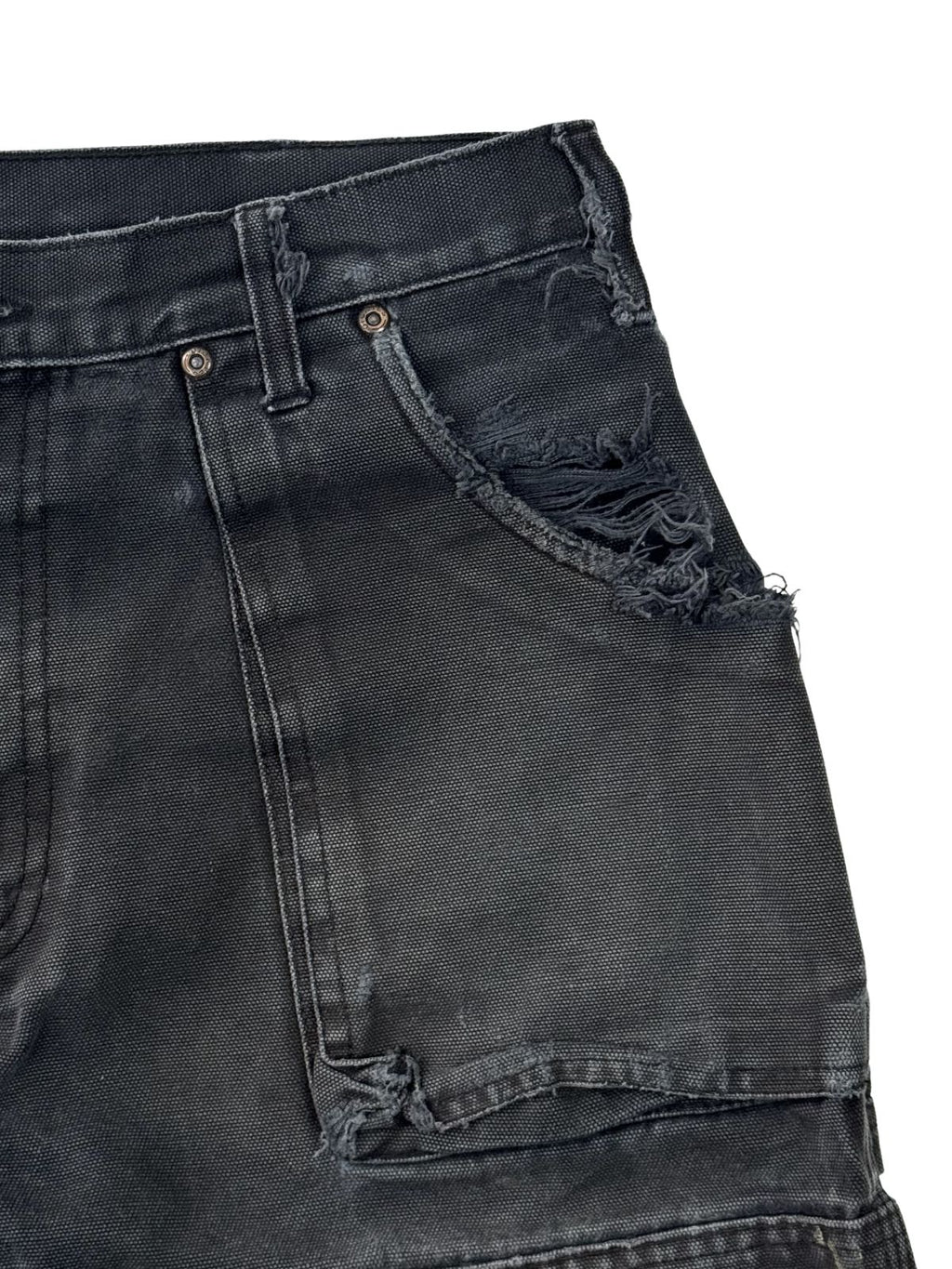 Detailansicht der linken Hosentasche einer thrashed Dickies Arbeitshose mit stark beschädigten Kanten und Textur.