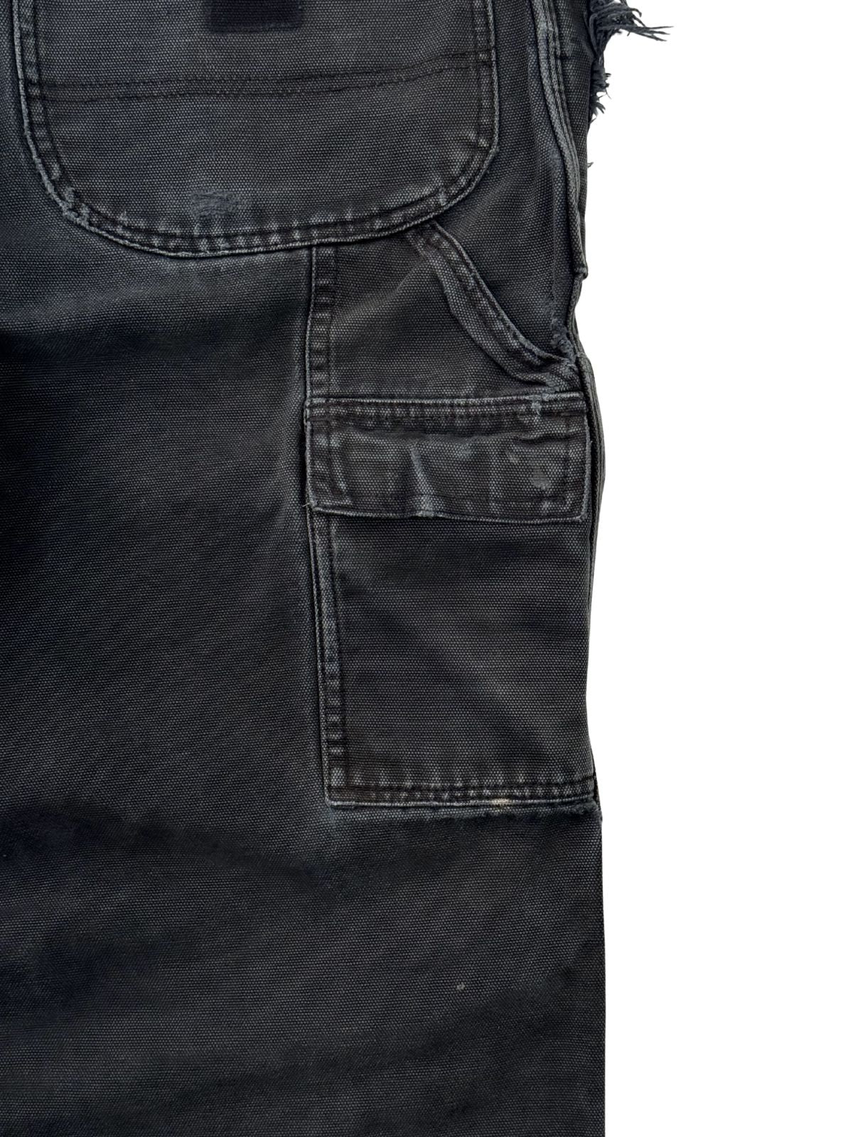 Nahaufnahme der seitlichen Utility-Tasche (Zollstocktasche) einer schwarzen Dickies Arbeitshose im Used-Look.