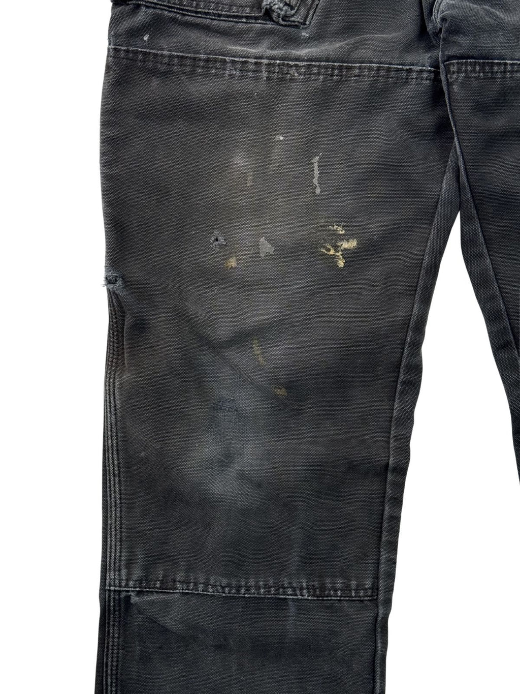 Detailaufnahme von Farbflecken und authentischen Verschmutzungen auf dem schwarzen Canvas-Stoff einer Vintage Workwear Hose.