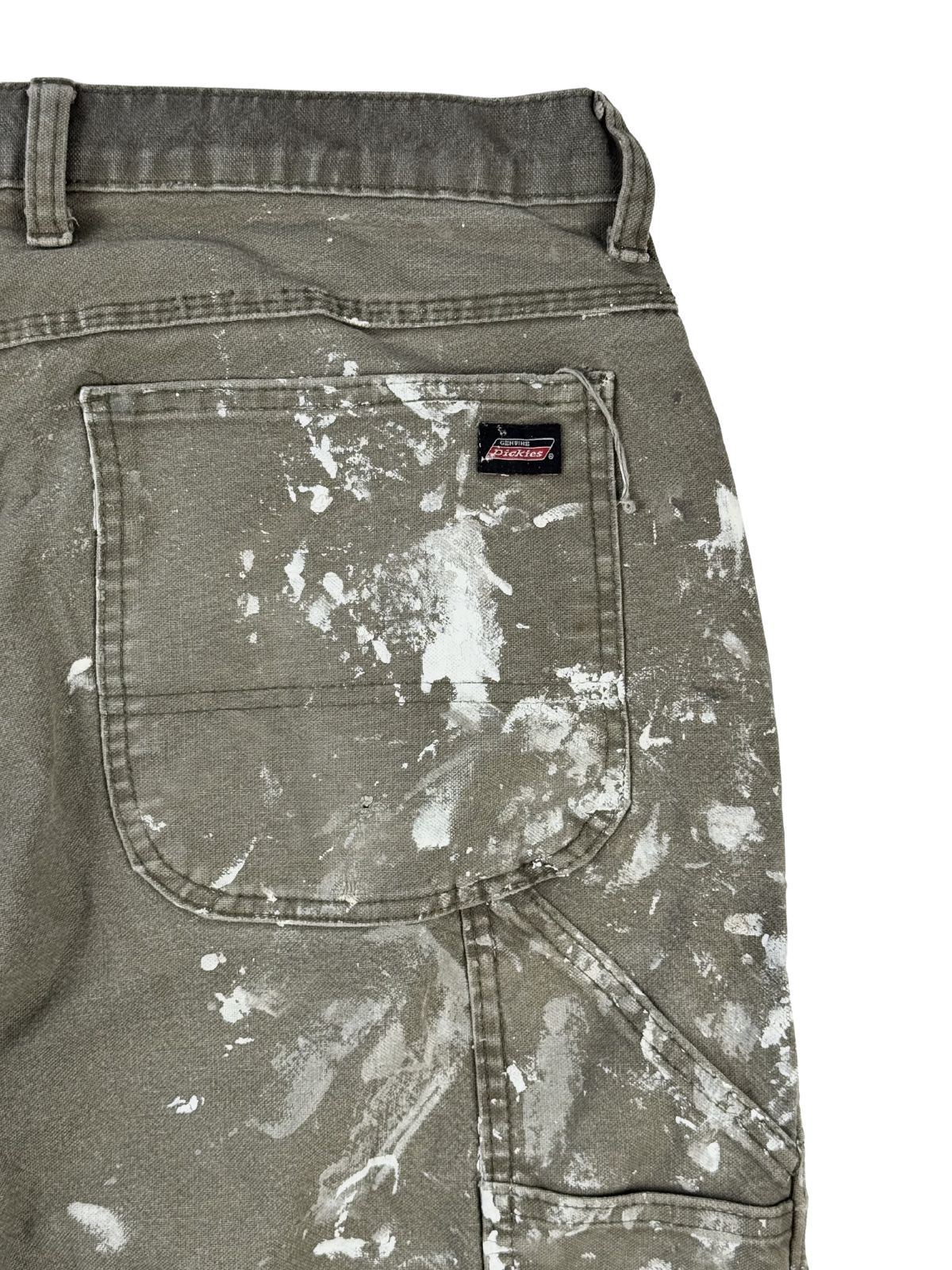 Nahaufnahme der rechten Gesäßtasche mit dem klassischen, kleinen Dickies-Logo-Patch an der oberen Taschenkante, umgeben von dichten weißen Farbspritzern.