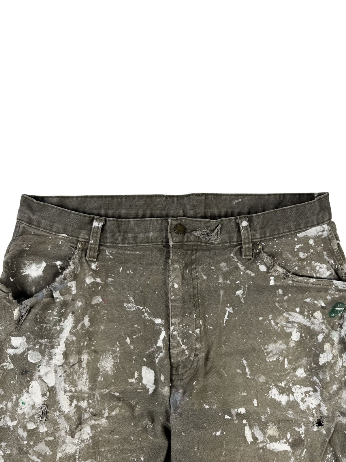 Detailansicht der vorderen Bundpartie. Die Vorderseite der Hose zeigt ein extremes Distressed-Muster aus weißen Farbschmierern sowie stark eingerissene, ausgefranste Ränder an beiden Eingriffstaschen.