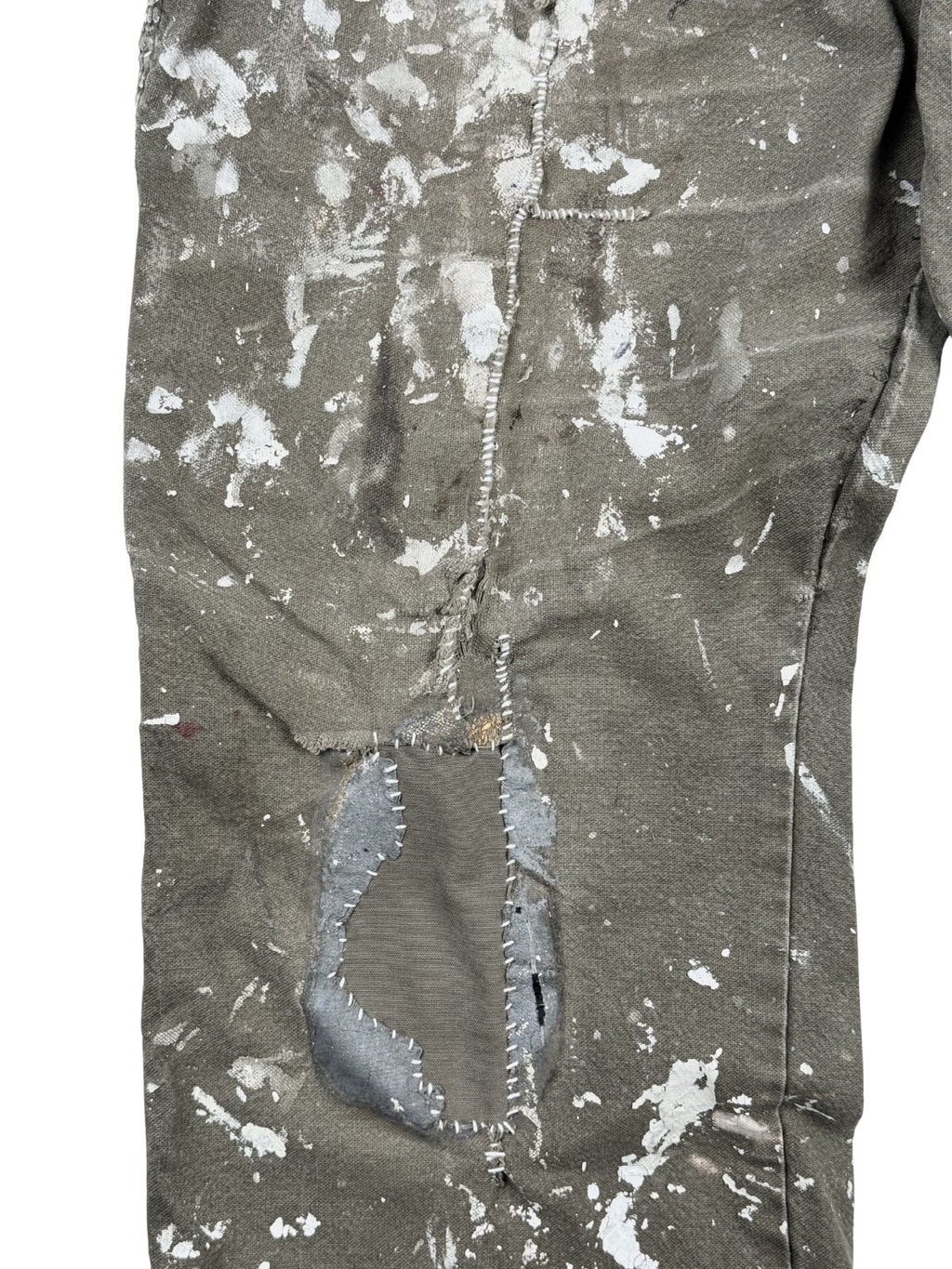Detaillierte Nahaufnahme einer aufwendigen Reparaturstelle (Hand-Repair) auf dem rechten Oberschenkel- und Kniebereich. Ein großer Riss wurde mit einem grauen Stoff-Flicken unterlegt und mit weißen Kontrastnähten per Hand vernäht, umgeben von dichten weißen Farbspritzern.