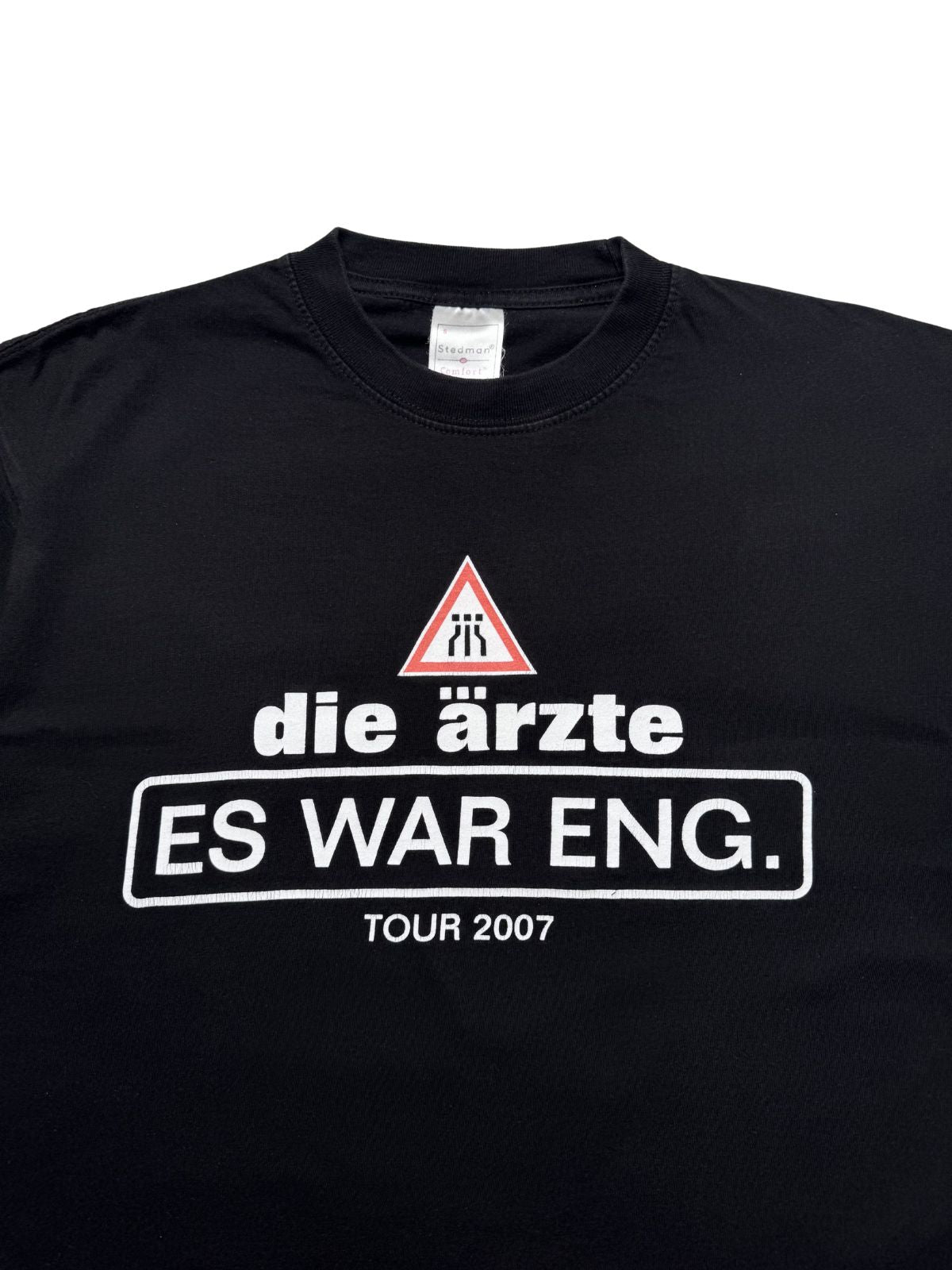 Nahaufnahme der vorderen Brustpartie mit Blick auf den gerippten Rundhalsausschnitt und den weißen „die ärzte - ES WAR ENG. TOUR 2007“ Siebdruck.