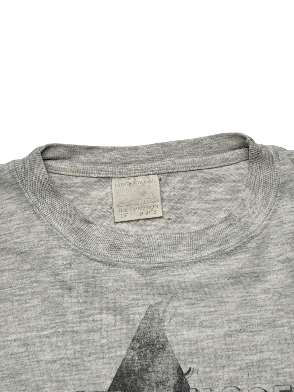 Nahaufnahme des Kragens mit dem gealterten, originalen Nackenetikett der Marke „International / The Champion of T-Shirts“ in Größe XL.