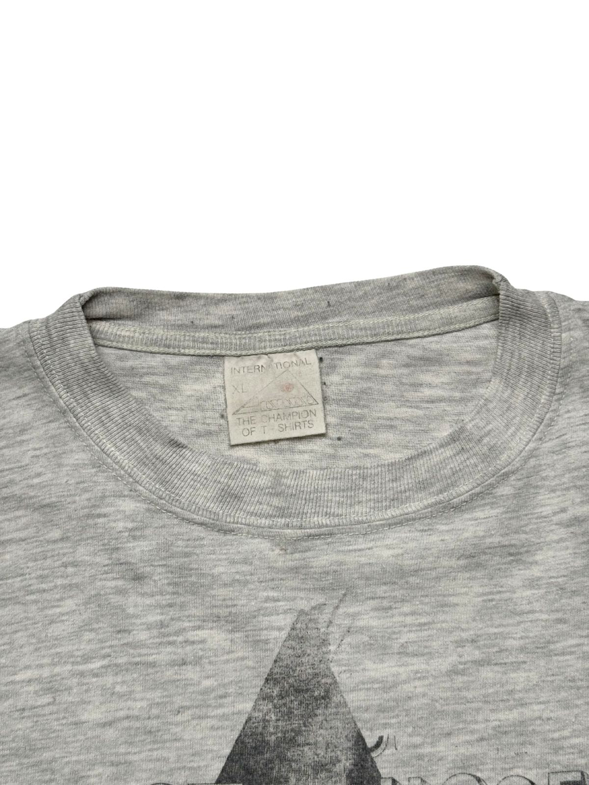 Nahaufnahme des Kragens mit dem gealterten, originalen Nackenetikett der Marke „International / The Champion of T-Shirts“ in Größe XL.