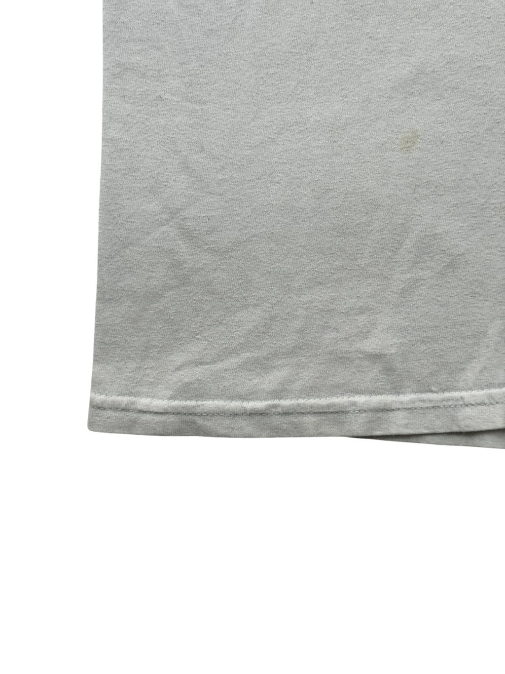 Detailaufnahme des unteren Saums mit doppelter Naht. Auf der rechten Seite des hellgrauen Baumwollstoffs ist ein kleiner, schwacher gelblicher Fleck zu erkennen.