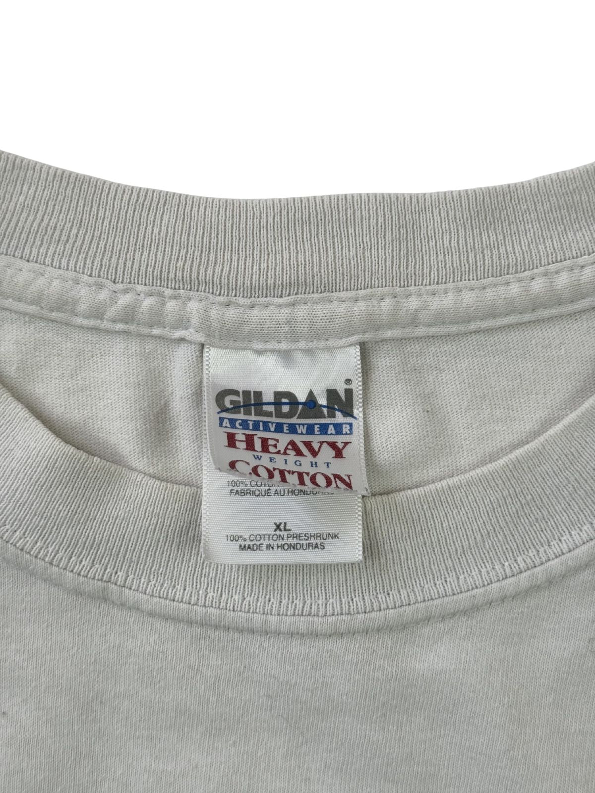 Makroaufnahme des Nackenetiketts. Das weiße Stofflabel der Marke Gildan zeigt das „Activewear Heavy Weight Cotton“-Logo, die Größe XL sowie den Hinweis „Made in Honduras“.