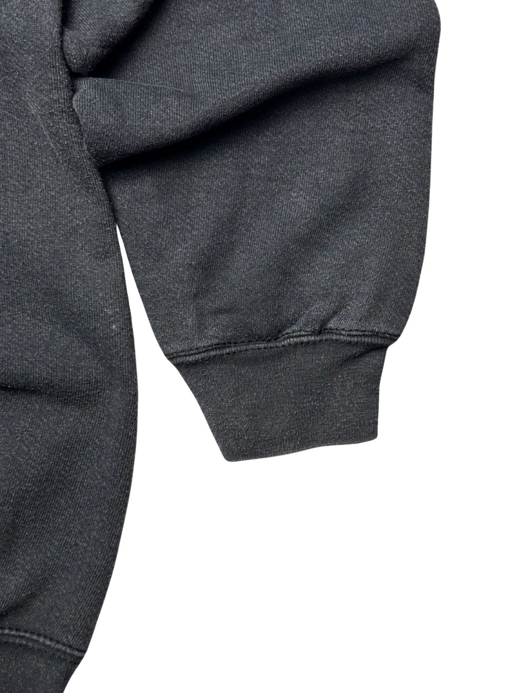 Detailansicht des elastischen Ärmelbündchens mit stabiler Nahtverarbeitung auf verwaschenem schwarzen Sweatstoff.