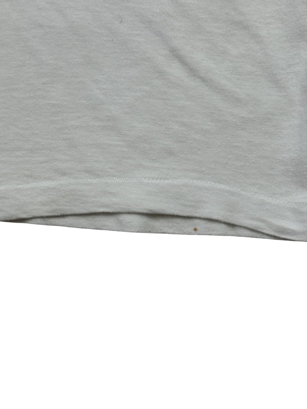 Detailaufnahme des unteren Saums mit Single-Stitch-Verarbeitung (Einfachnaht) am weißen Sigmund-Freud-T-Shirt. Zu sehen ist ein winziger, punktförmiger brauner Fleck (Stain) direkt an der unteren Stoffkante zur genauen Dokumentation des Vintage-Zustands.