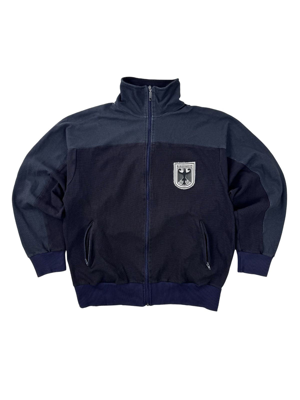 Vorderansicht einer dunkelblau eingefärbten Vintage Bundeswehr Trainingsjacke der 90er Jahre mit handgesticktem Bundesadler-Logo auf weißem Patch.