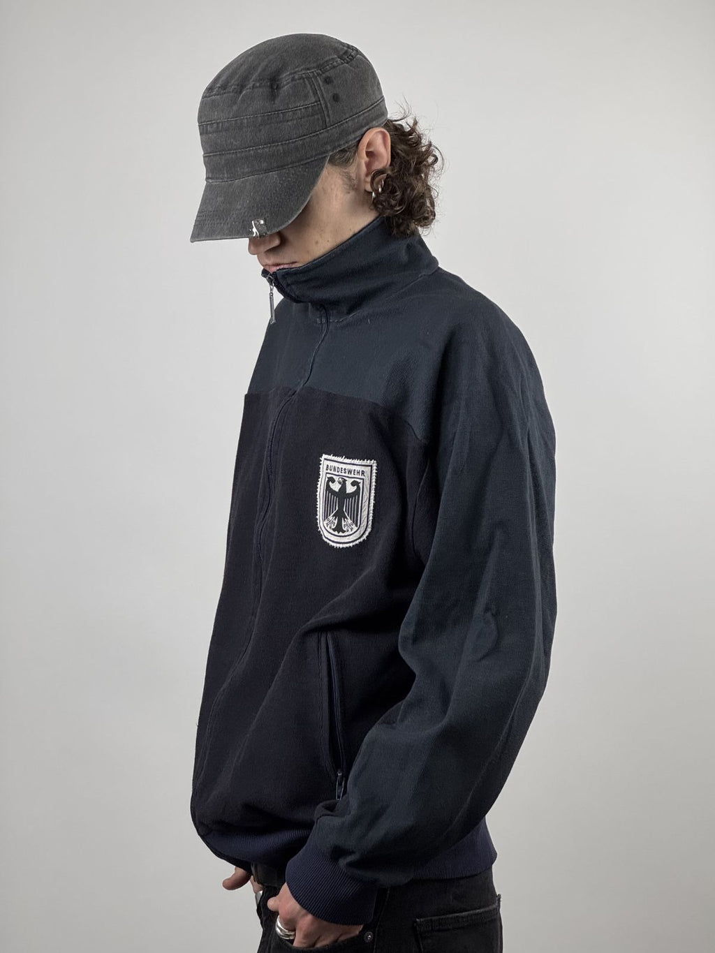 Seitenprofil der Sportjacke; zeigt die Ärmelform und die Platzierung des Bundeswehr-Logos im getragenen Zustand.