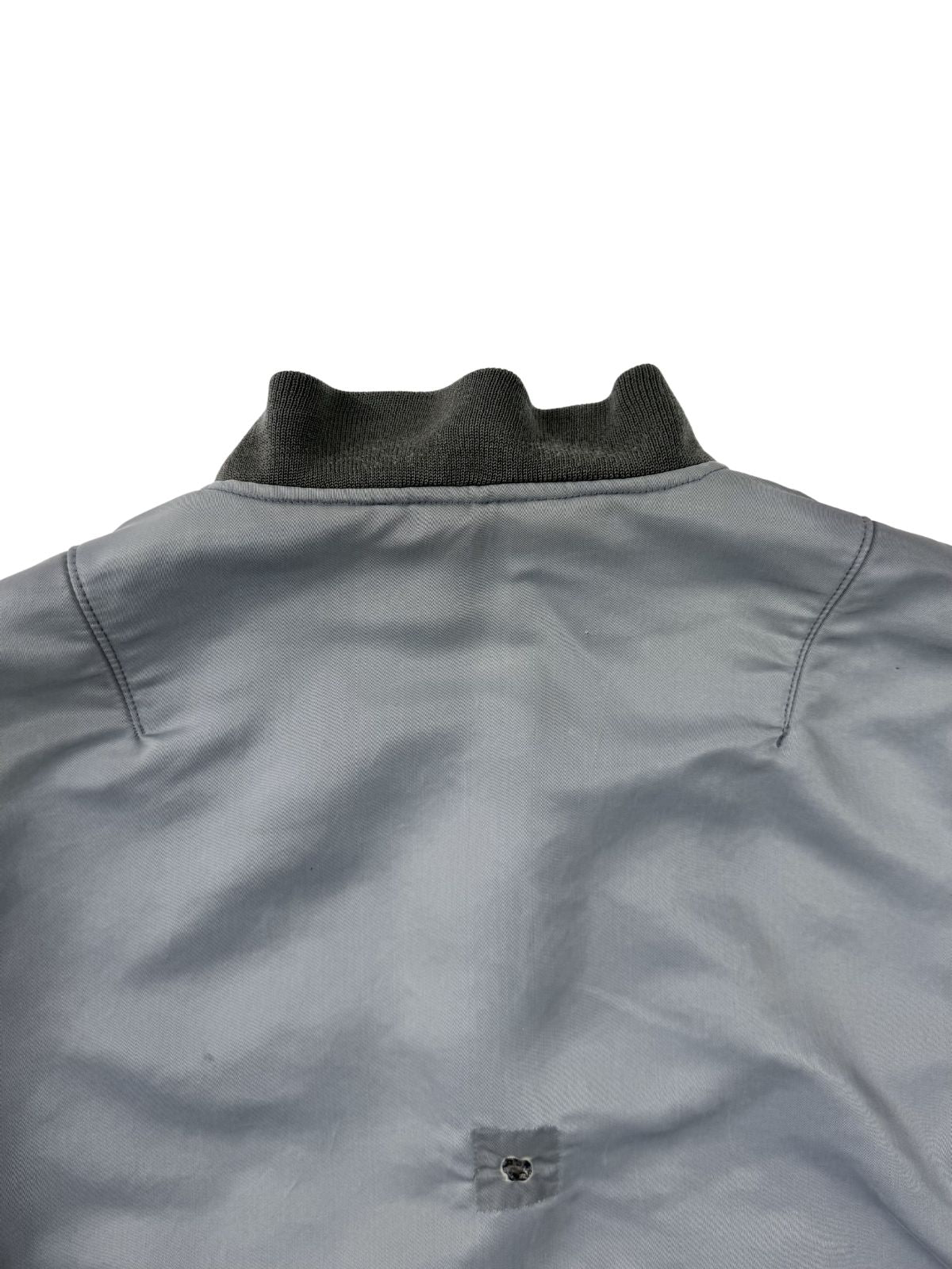 Makroaufnahme der Rückseite des Kragens und Beschädigungen am Rückenmaterial der vintage Jacke; zeigt authentische Löcher und die Textur des gealterten Nylons.