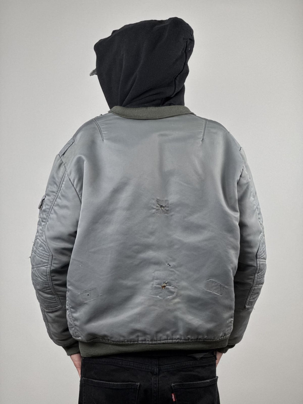 Rückansicht des Models in der verwaschenen Fliegerjacke; verdeutlicht die Platzierung der authentischen Löcher am Rücken und das markante Sun-Fading des Bundeswehr-Originals.
