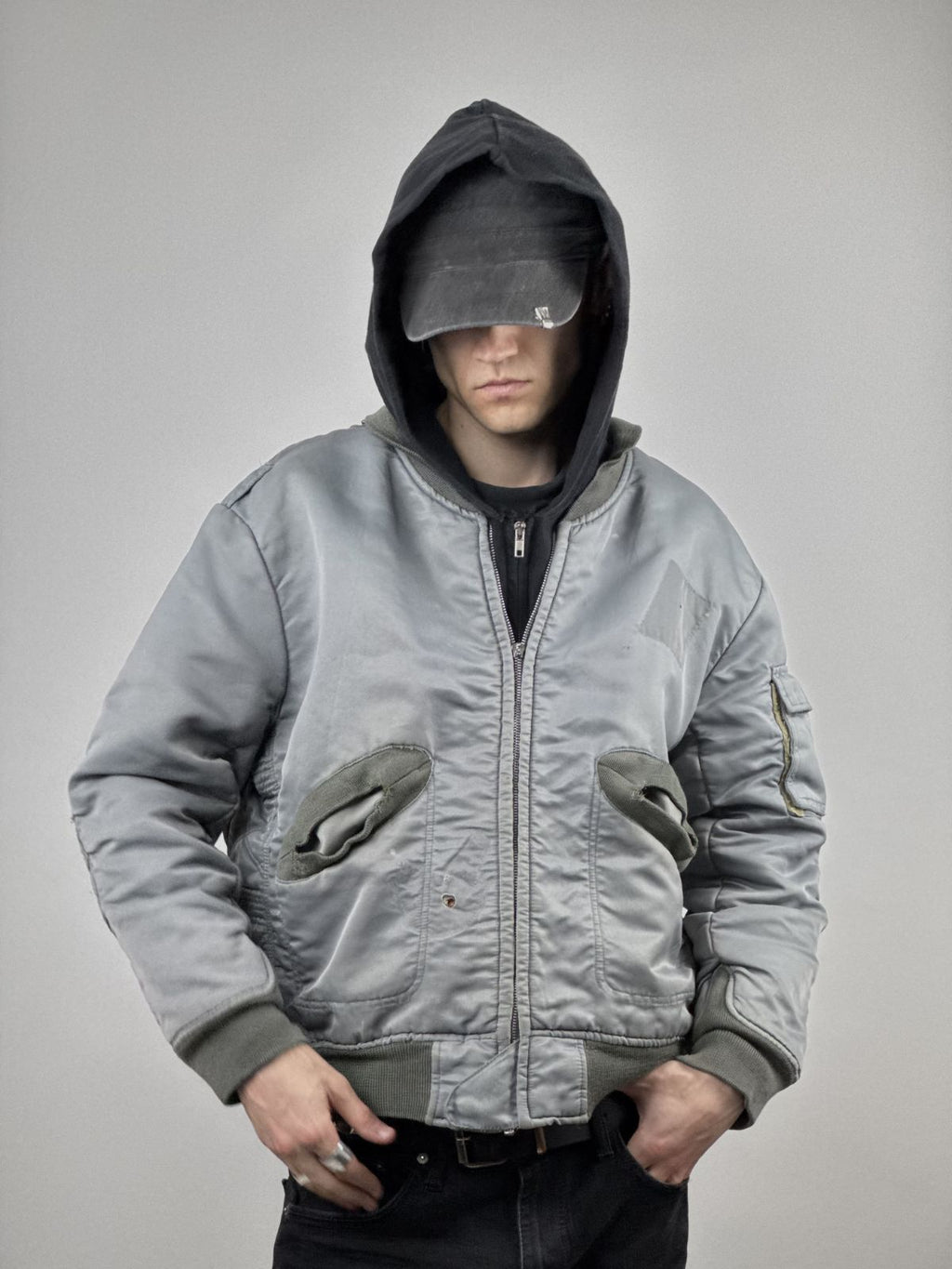 Model trägt die verwaschene Bomberjacke kombiniert mit einem schwarzen Hoodie; zeigt die boxy Passform und den authentischen Military-Streetwear-Look.
