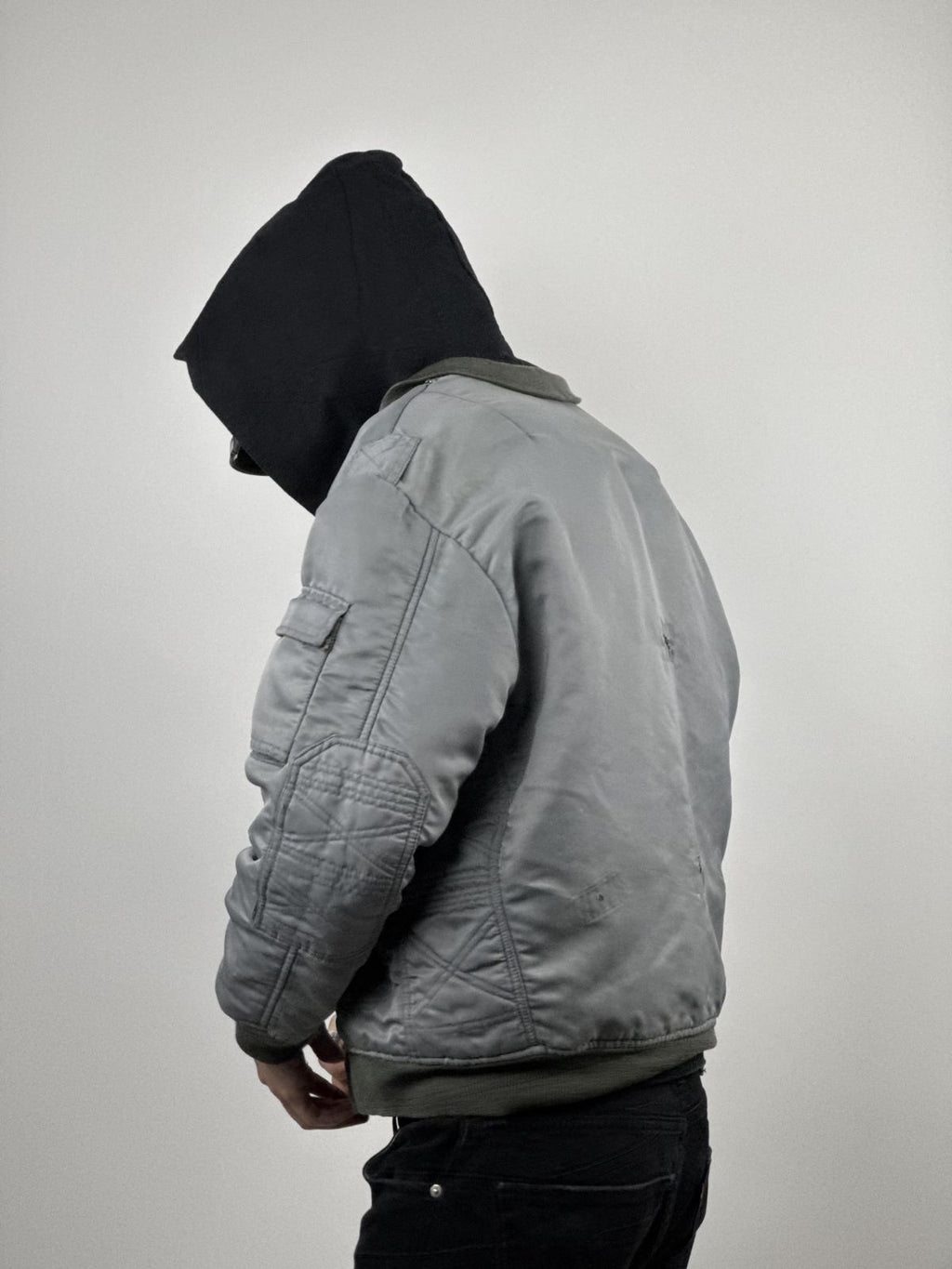Seitenprofil des Models in der hellblauen Fliegerjacke; Fokus auf dem Diamond-Quilt-Muster an den Ärmeln und der utility arm pocket.