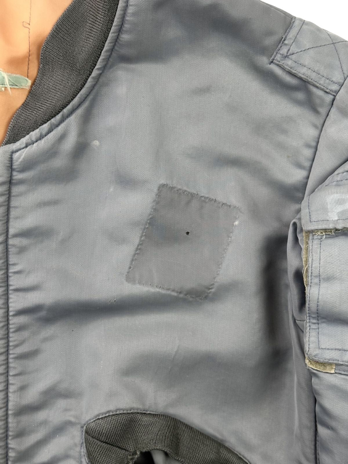 Nahaufnahme der Brustseite; zeigt den quadratischen "Shadow Fade" (Farbschatten) eines entfernten Patches sowie ein kleines authentisches Loch im Material.