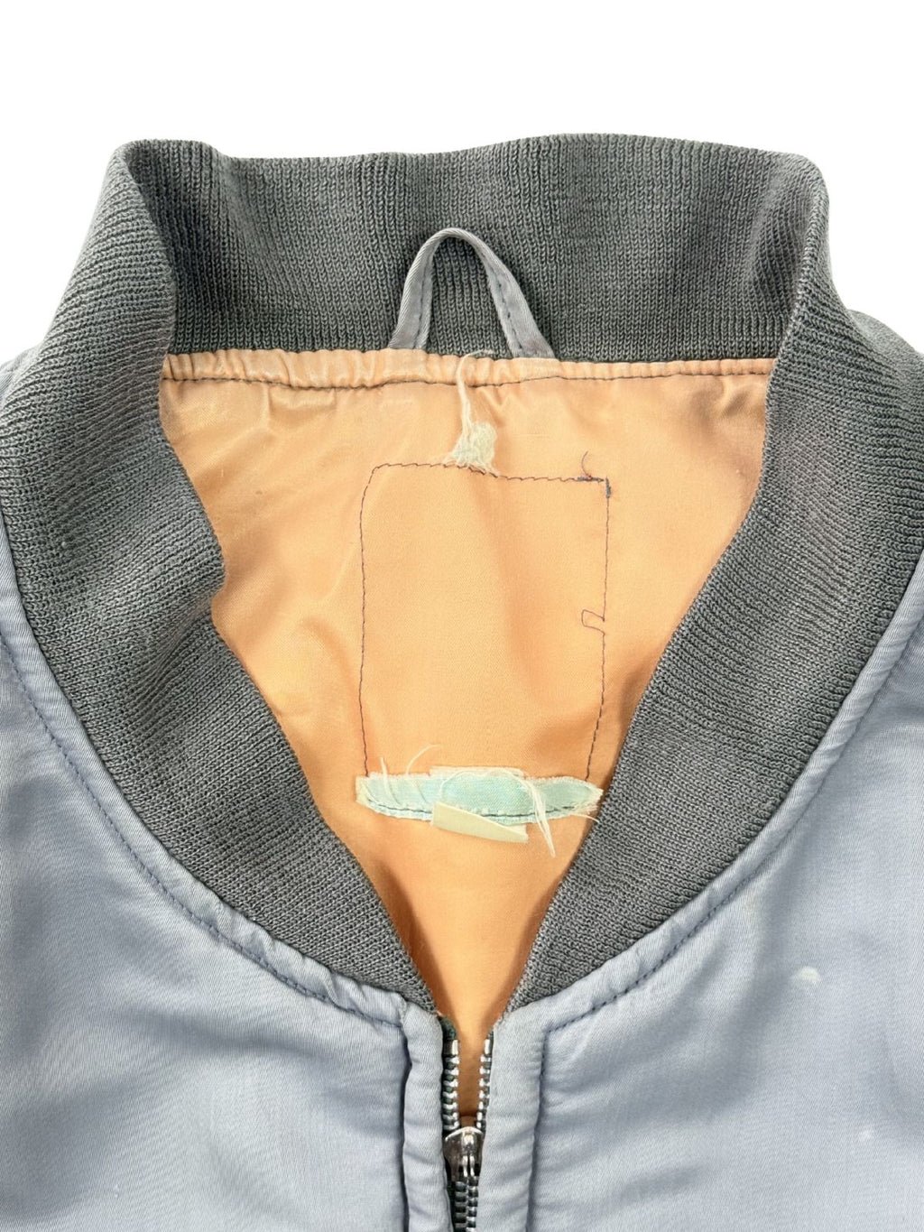 Detailansicht der Krageninnenseite; zeigt die Nahtreste des entfernten Original-Etiketts auf dem orangefarbenen Lining.