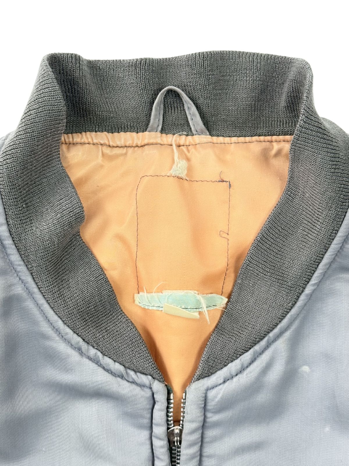 Detailansicht der Krageninnenseite; zeigt die Nahtreste des entfernten Original-Etiketts auf dem orangefarbenen Lining.