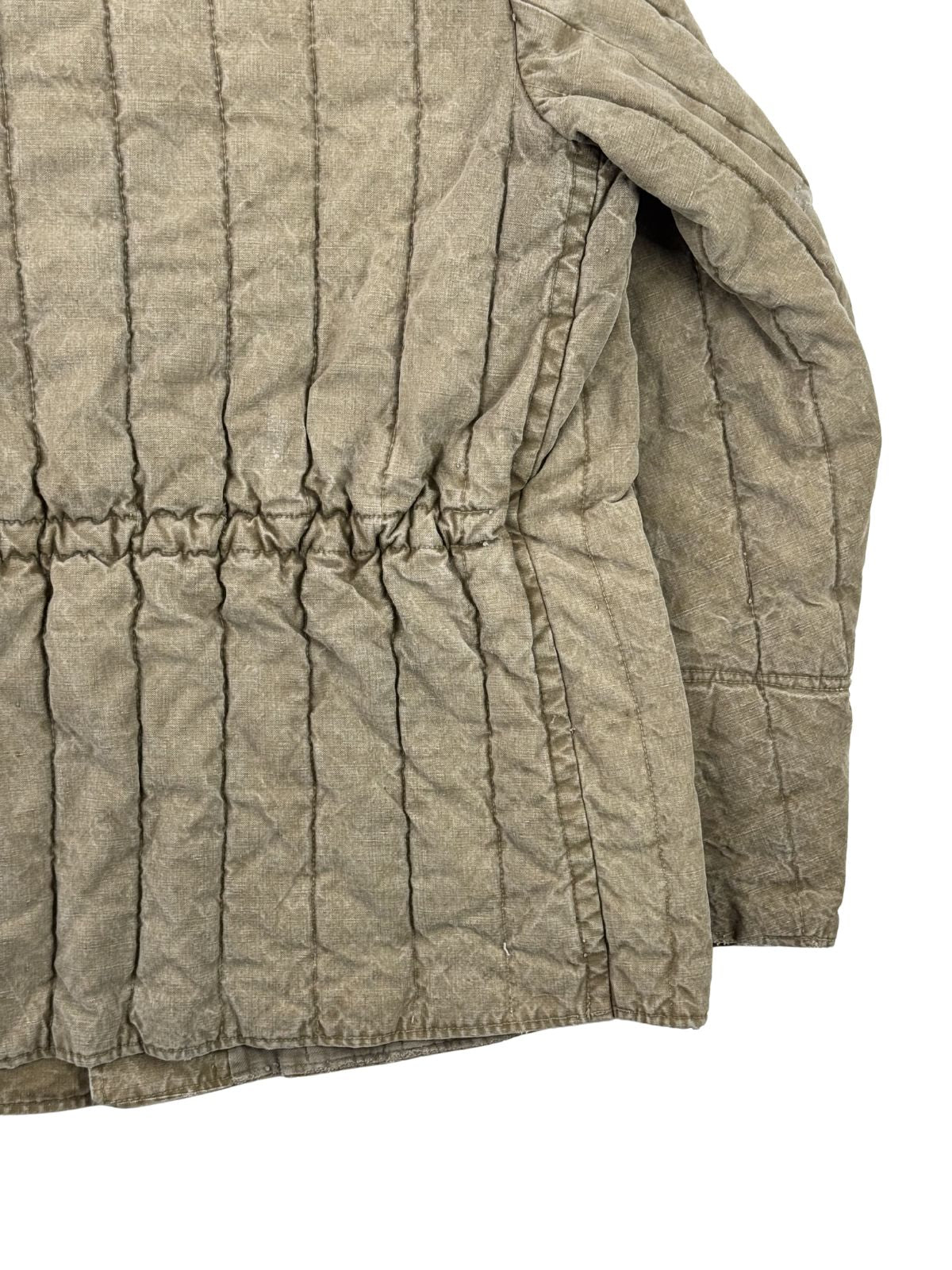 Detailansicht der seitlichen Rückpartie der gepolsterten Jacke. Gezeigt wird die starke Raffung des Stoffs durch den elastischen Taillenzug sowie der Ansatz des gesteppten Ärmels.