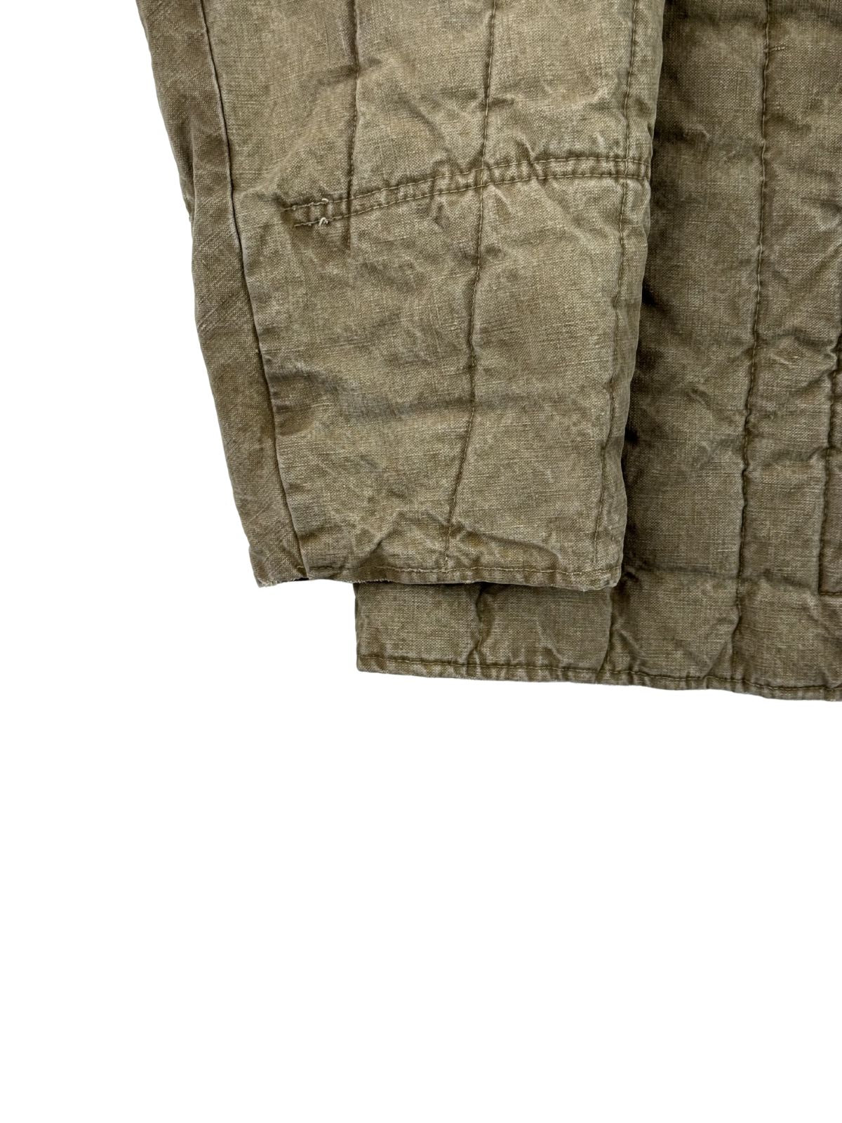 Detailaufnahme des rechten Ärmels und des unteren Saumbereichs der gesteppten Militärjacke. Gut zu erkennen sind die robusten Verstärkungsnähte oberhalb des Ärmelbündchens sowie die strukturierte, verwaschene Beschaffenheit des alten Baumwollstoffs.