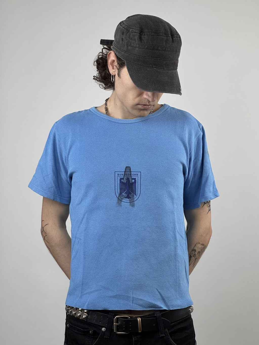 Vorderansicht eines hellblauen Vintage Bundeswehr Sport-T-Shirts aus den 1980ern mit einem dunkelblauen Brustprint, der den Bundesadler in einem Wappen zeigt.