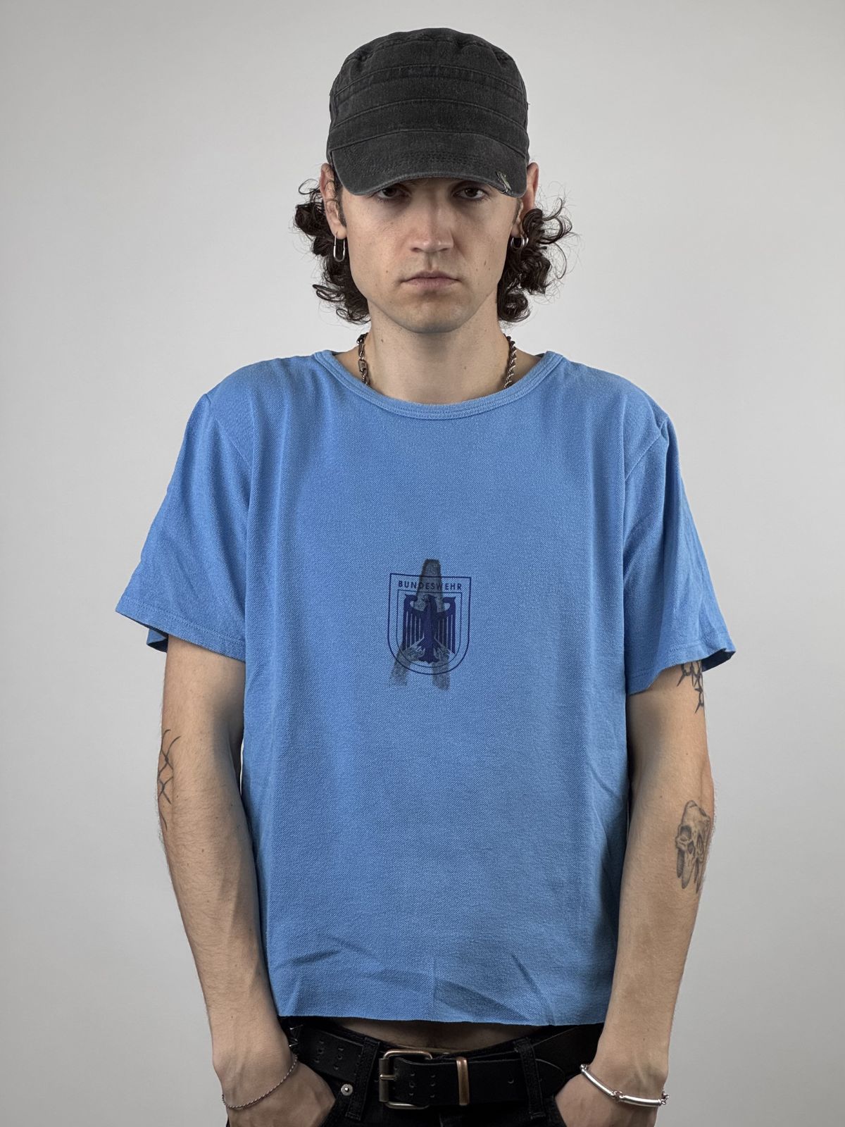 Ein Model präsentiert das hellblaue Bundeswehr-Sport-T-Shirt; Fokus auf dem Grafik-Brustprint und der schmalen, authentischen 80er-Jahre-Passform.