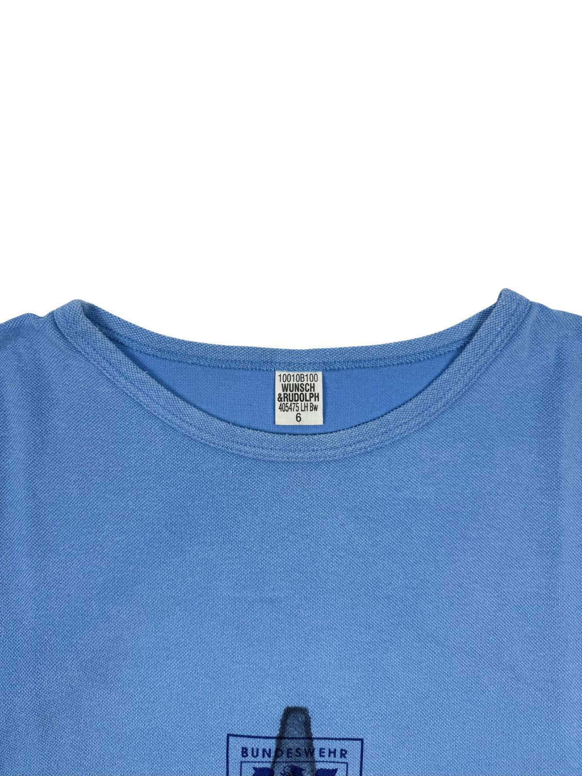 Nahaufnahme des Nackenetiketts: Weißes Etikett des Herstellers „WUNSCH RUDOLPH“, Größe 6, eingenäht in den hellblauen T-Shirt-Kragen.