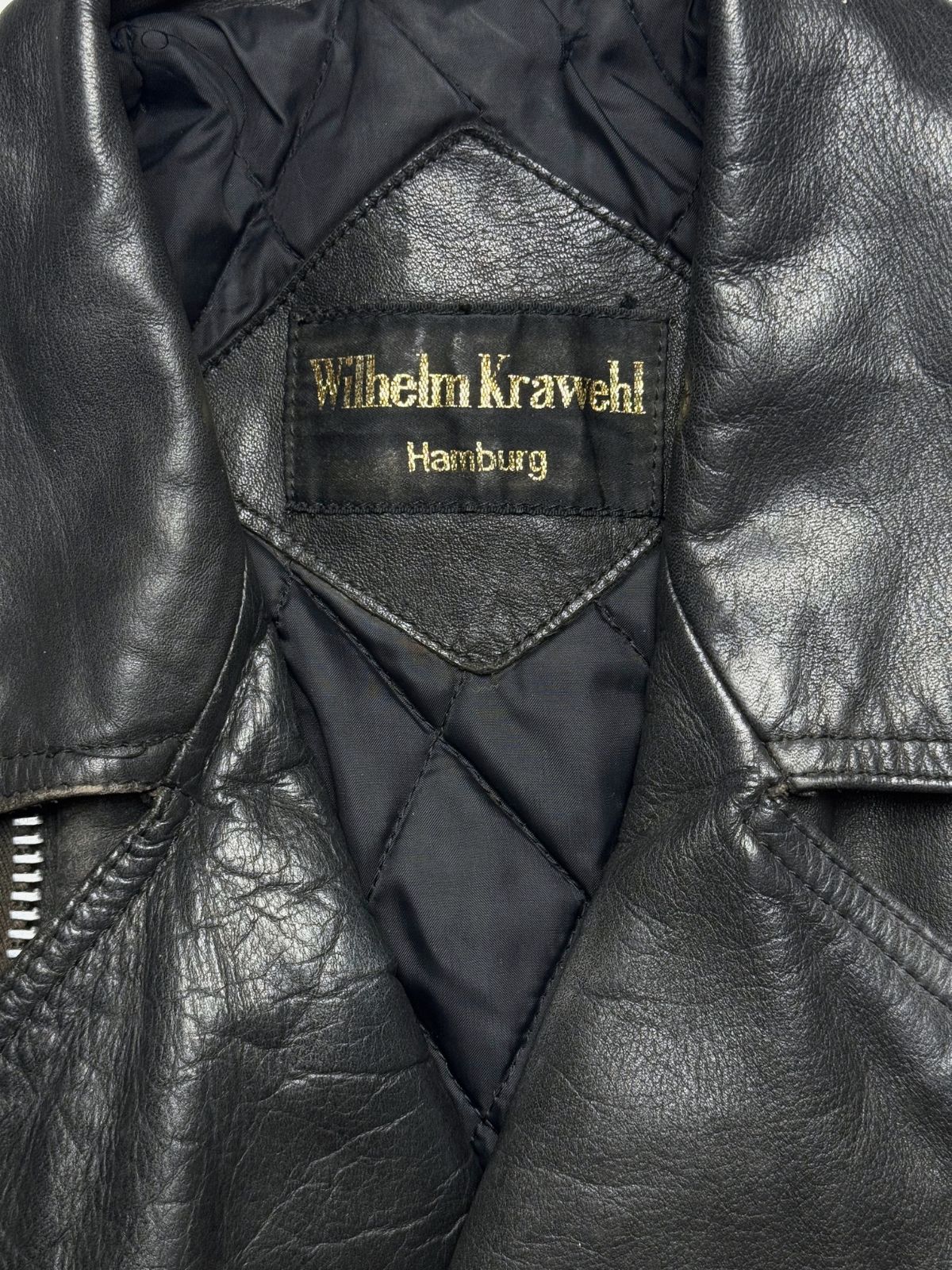 Nahaufnahme des inneren Kragenbereichs mit dem gewebten, gold-gestickten Markenetikett „Wilhelm Krawehl Hamburg“ auf dem rautenförmigen Leder-Patch.