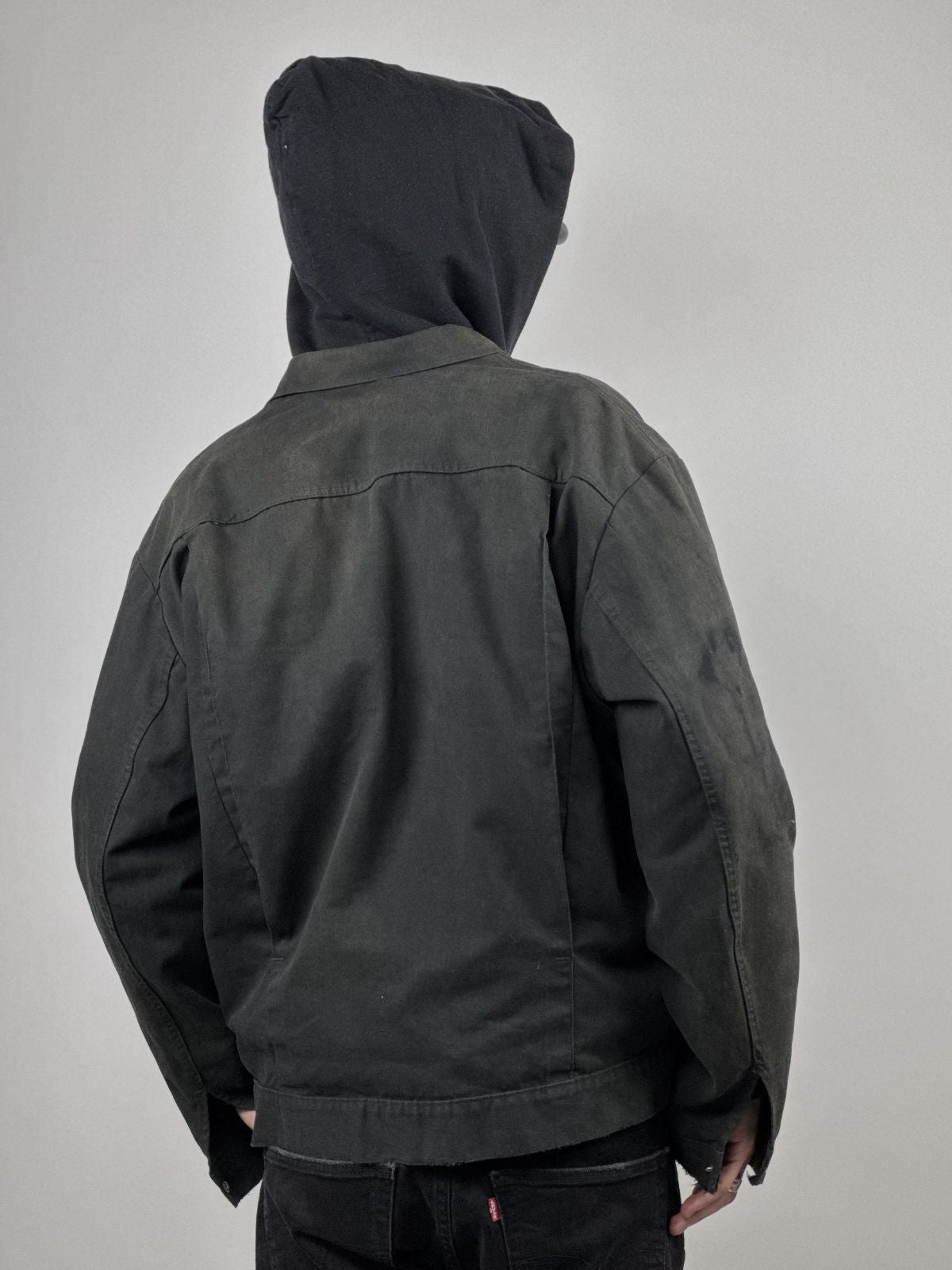 Rückseite des Models in der distressed Workwear Jacke; verdeutlicht den kurzen Schnitt und den Sitz der Schulterpartie.