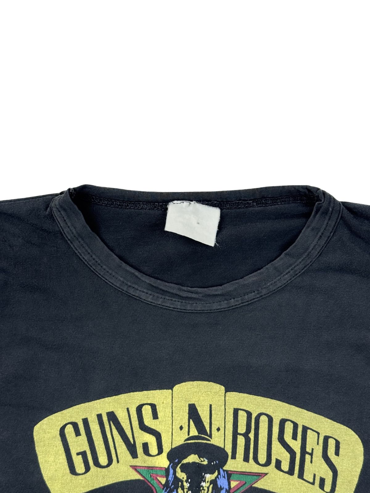 Nahaufnahme des Rundhalsausschnitts mit einem stark verwaschenen, weißen Nackenetikett (Neck Tag) über dem gelben Band-Schriftzug.