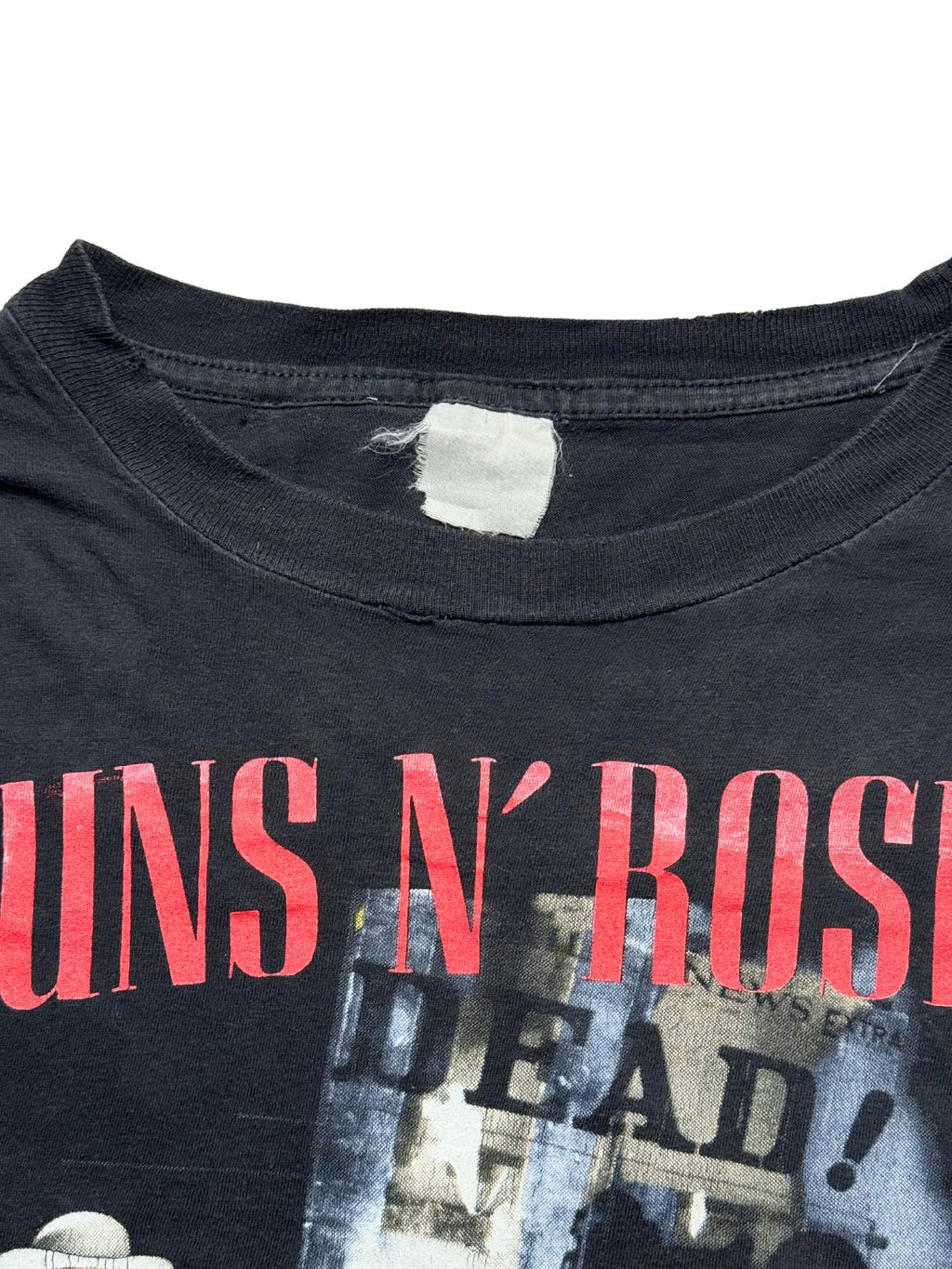 Detailansicht der vorderen Brustpartie mit geripptem Rundhalsausschnitt, dem roten „GUNS N’ ROSES“-Schriftzug und dem verwaschenen Stoffetikett.