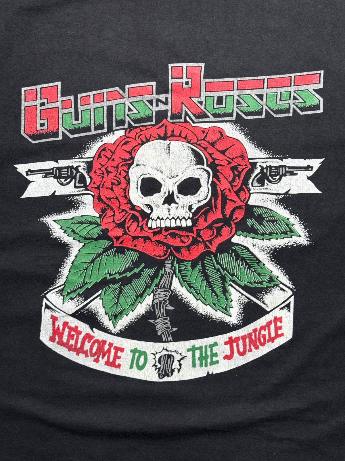 Detailansicht des vorderen Grafikprints mit dem rot-grünen Guns N' Roses Logo, der roten Rose mit Schädel und dem Banner „WELCOME TO THE JUNGLE“.
