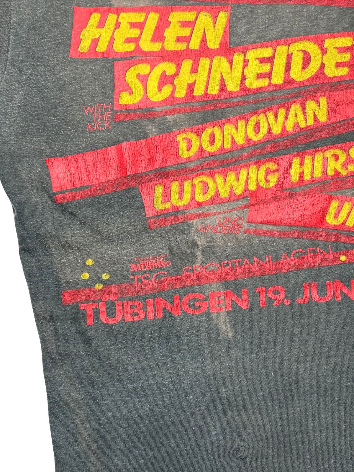 Nahaufnahme des Festival-Siebdrucks mit Bändern, Künstlernamen und Sponsoring-Details (Mustang) auf verwaschenem Stoff.