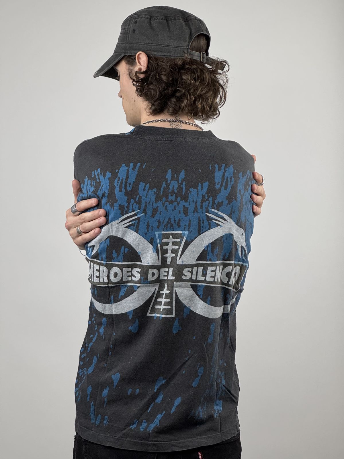 Rückansicht des getragenen Band-Shirts; zeigt das markante Rückenlogo und die Kombination mit einer schwarzen Streetwear-Mütze.