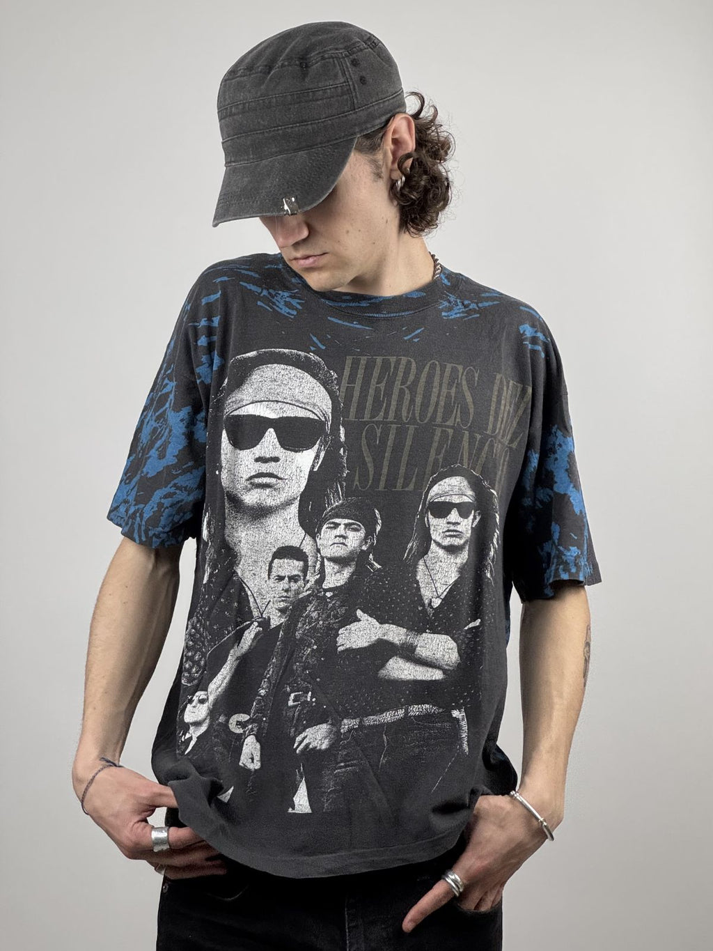 Ein Model trägt das Héroes del Silencio AOP Shirt; die lockere Passform und das auffällige Porträt-Design des spanischen Rock-Klassikers werden deutlich.
