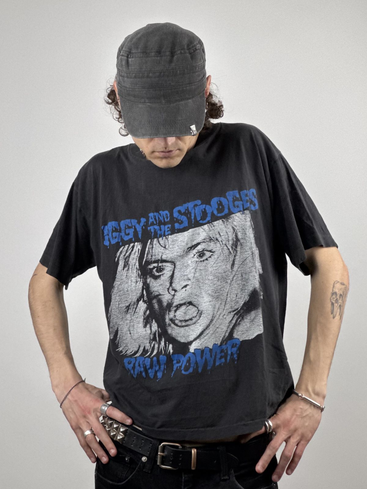 Ein Model mit Mütze trägt das Iggy & The Stooges Shirt im Punk-Rock-Look; Fokus auf dem provokanten Grafikprint und der authentischen 80er-Jahre-Passform.