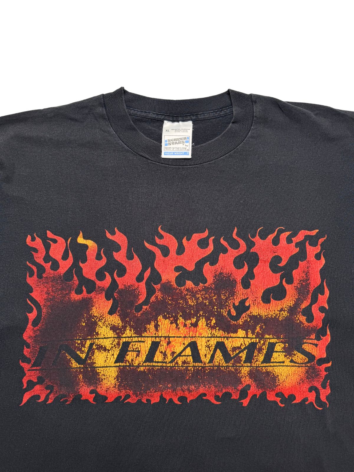 Detailansicht der vorderen Brustpartie mit geripptem Rundhalsausschnitt, dem gelb-roten Flammen-Print und dem Screen-Stars-Nackenetikett.