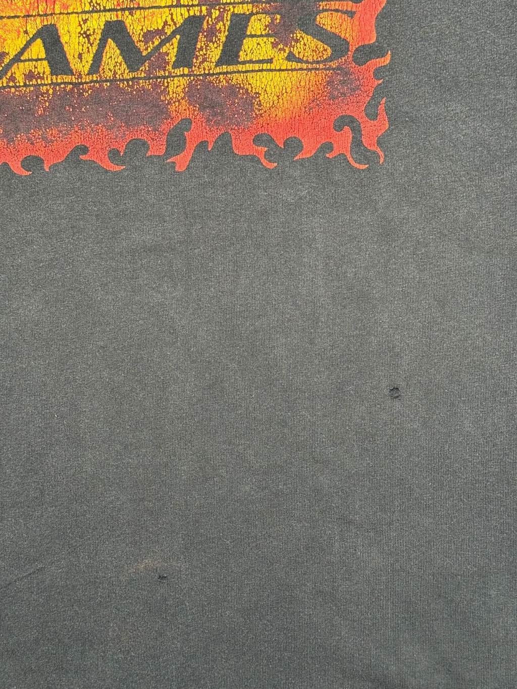 Makroaufnahme der vorderen Stofffläche unterhalb des Flammen-Prints mit zwei feinen Pinholes im Material.