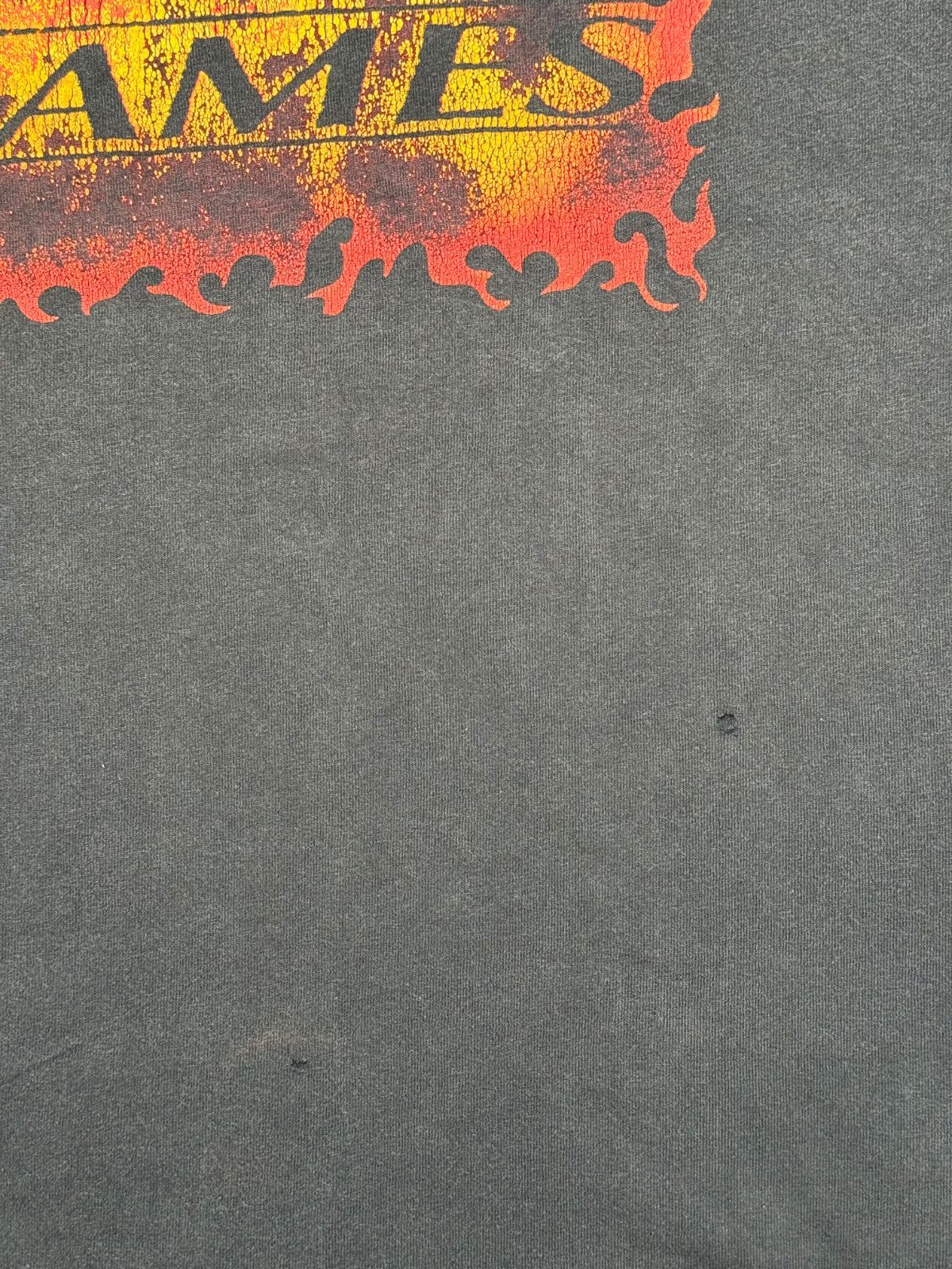 Makroaufnahme der vorderen Stofffläche unterhalb des Flammen-Prints mit zwei feinen Pinholes im Material.