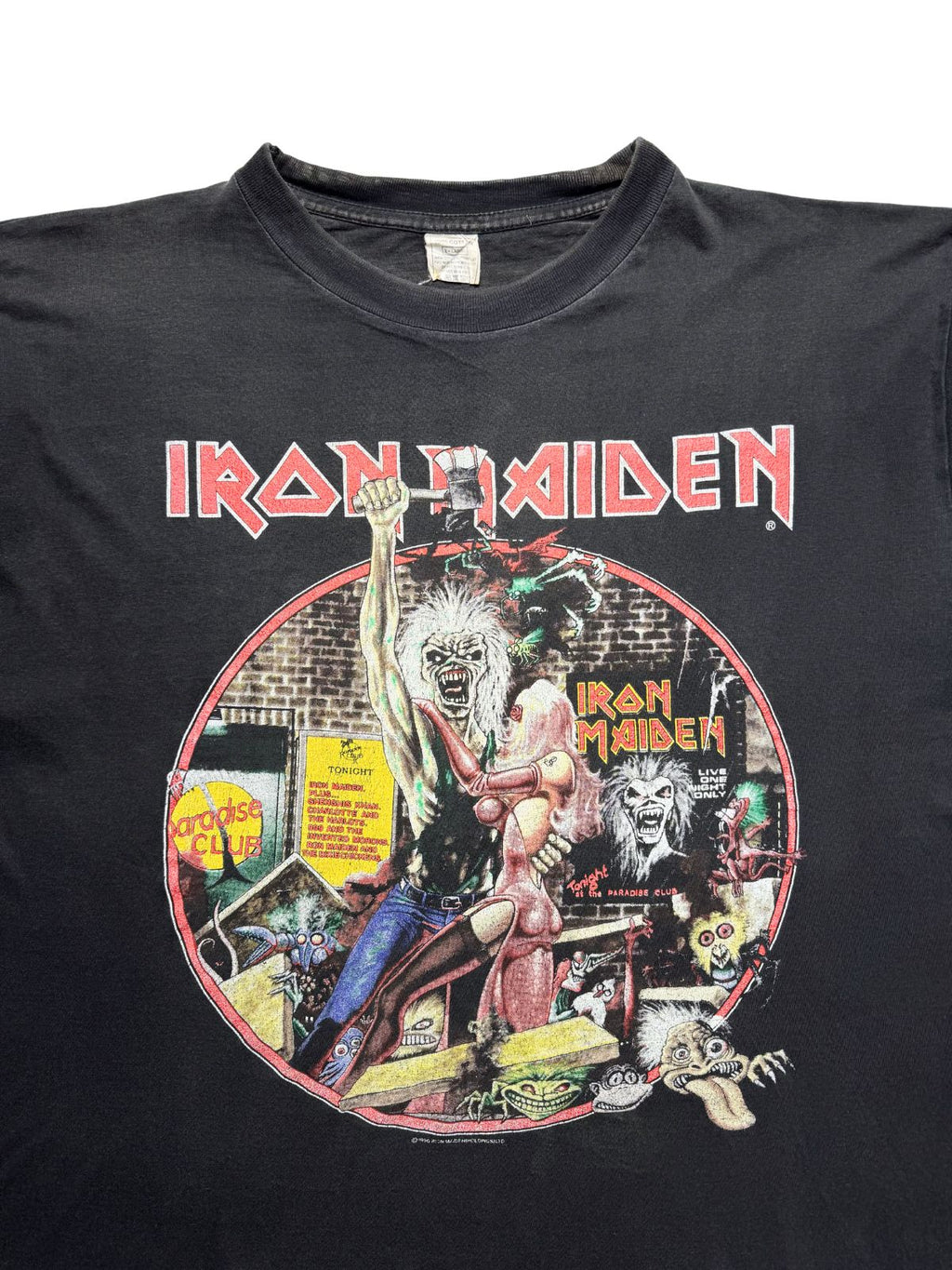 Detailansicht der oberen Frontpartie mit dem roten „IRON MAIDEN“-Logo, dem Eddie-Single-Coverart und dem verwaschenen weißen Nackenetikett.