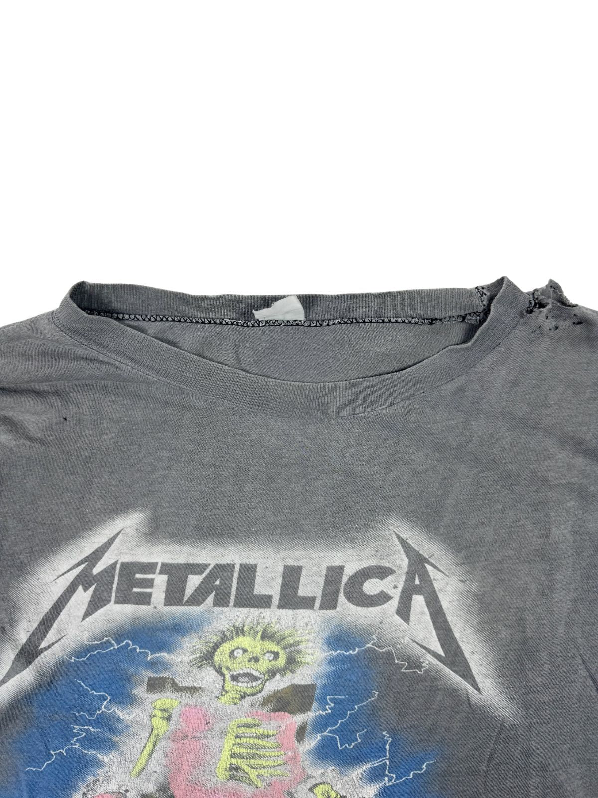 Nahaufnahme des zerfransten Rundhalsausschnitts und des oberen Teils der Metallica-Grafik; zeigt die starke Textur des Vintage-Baumwollstoffs.