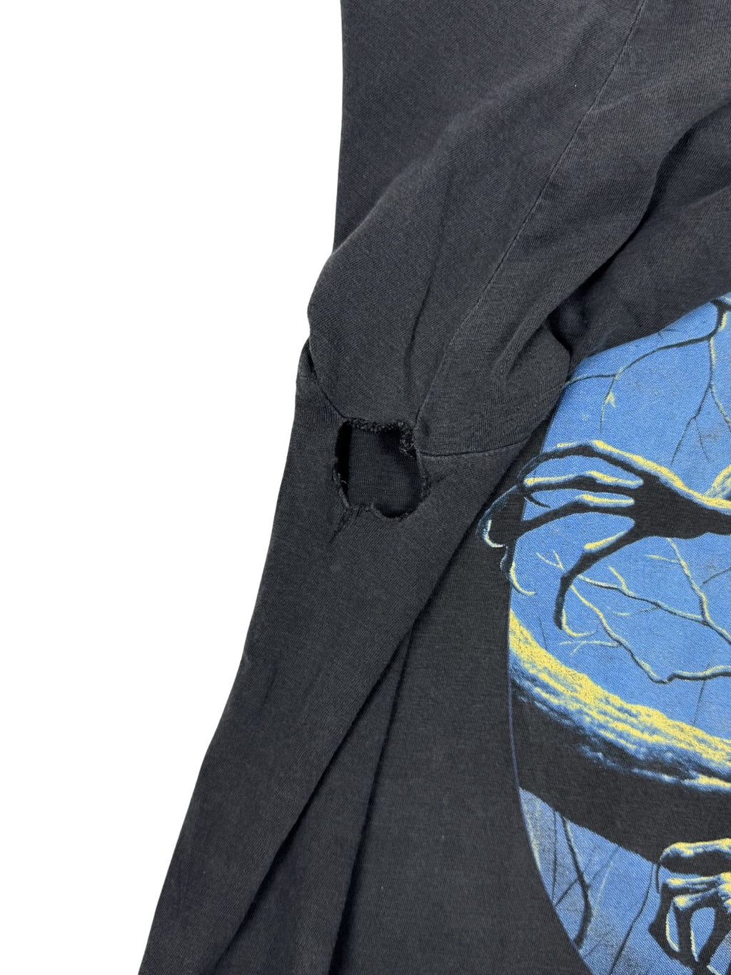 Transparente Aufnahme einer Beschädigung; zeigt ein größeres Loch im Achselbereich (Distressed Condition) des Vintage Iron Maiden Shirts.