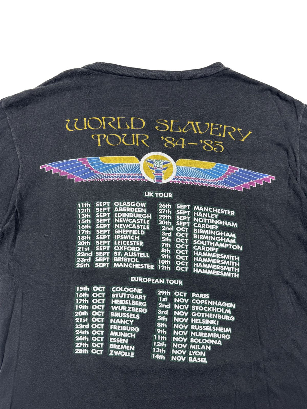 Nahaufnahme der Rückseite eines Iron Maiden World Slavery Tour Shirts; zeigt die Liste der Tourdaten 1984 für UK und Europa unter dem geflügelten Skarabäus-Logo.